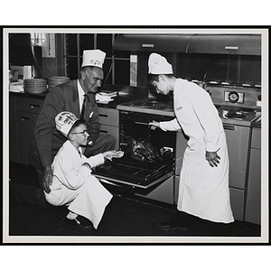 Overseer Forrester A. Clark and two members of the Tom Pappas Chefs' Club pose with a cooked turkey in an open oven