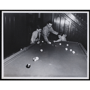 A Man showing a boy how to take a shot in a pool game