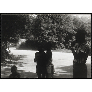 A Child whispers into another child's ear during an activity at camp, while an adult observes