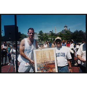 Executive Director Jerry Steimel (right) holds a framed print with a man during the Battle of Bunker Hill Road Race