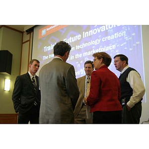 Five people stand in front of a projector screen at the Training Future Innovators Entrepreneurs Panel