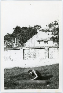 Naomi Jaffe examining unexploded bomb, in front of ruins