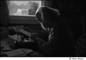 Ram Dass at typewriter: Ram Dass seated at a typewriter, with a portrait of Neem Karoli Baba in the background