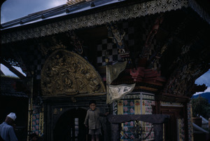 Child stands near the entrance to a small Hindu temple in Kathmandu