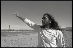 Peace encampment activist waving at a passing vehicle on the road near the entrance to the Nevada Test Site