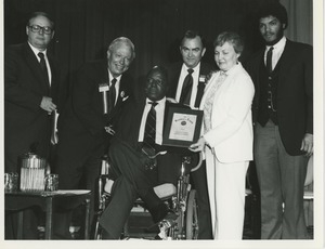 Curtis Brewer holds his President's Trophy with a group of people