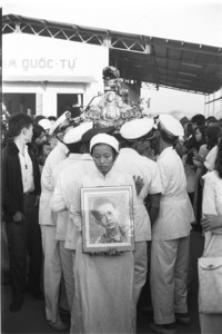 Portrait of 15 year old Le van Ngoc carried by his sister; Saigon.