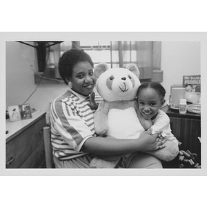 Woman and child hugging stuffed toy bear