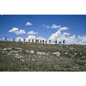 Youth hiking in line along ridge of a hill
