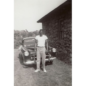 An unknown man poses in front of an automobile