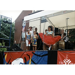 Young girl on the stage at Festival Betances dancing in a bright red skirt.