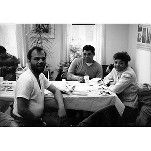 Men and women at a table in the Inquilinos Boricuas en Acción offices eating cake.