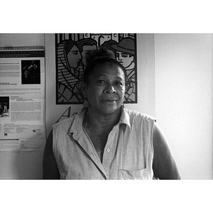 Woman in a sleeveless blouse standing in front of a poster.