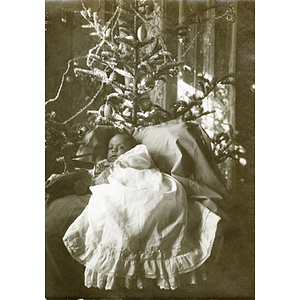 Baby in front of a decorated Christmas tree