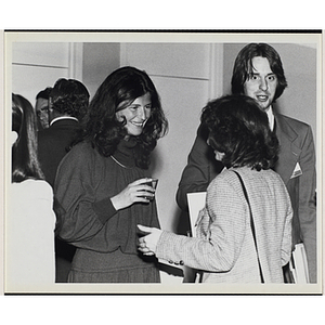 Two women stand and converse while a man walks past at a Boys' Club event