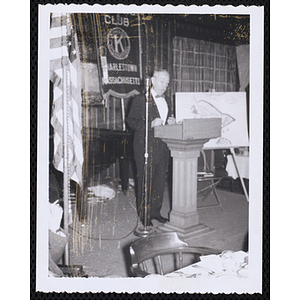 A man speaking from the podium at the Kiwanis Club's Bunker Hill Postage Stamp Luncheon