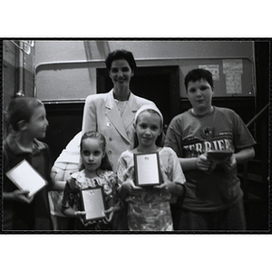 Heather Khan, a former news anchor, posing with four boys and girls holding their awards at a Kiwanis Awards Night