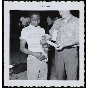 A man presents an award ribbon to a boy's pet during a Boys' Club Pet Show