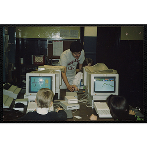 A man tutors a girl in a computer lab