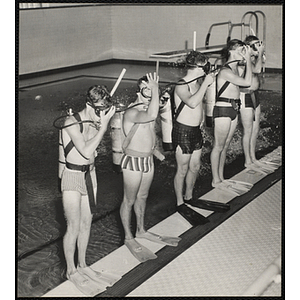 Five men wearing scuba gear stand at the edge of a natatorium pool