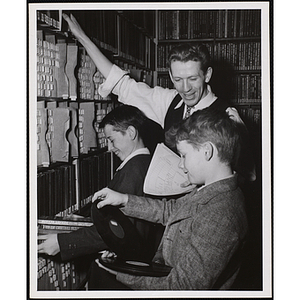 Two boys and a man pose for a shot in a vinyl record library