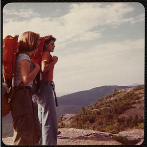 Two teenage girls stand on a mountain during a hike