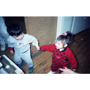 Young boy and girl hold hands at a Chinese Progressive Association holiday party