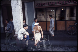 Foshan: two young men sitting on cart, laughing, chatting