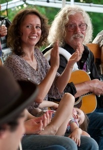 Sarah Lee Guthrie with young girl and Arlo Guthrie, applauding on stage at the Clearwater Festival