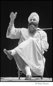 Yogi Bhajan seated onstage, talking to the audience at the Kohoutek Celebration of Consciousness