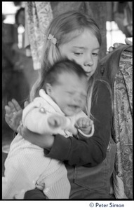 Young girl holding a fidgety infant, Lama Foundation