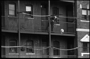 Man looking at a cat caught in the railing of fire escape on an old apartment house