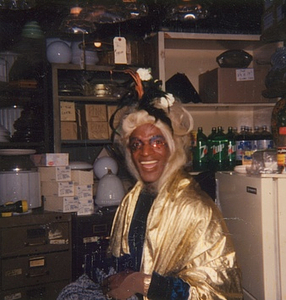 Photographs of Marsha P. Johnson Wearing a Gold Cape in a Supply Closet