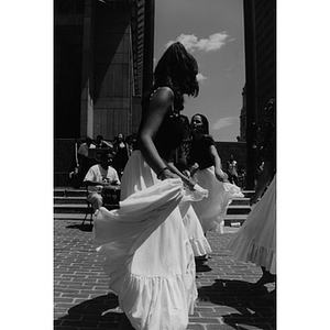 Girls hold their skirts as they dance in Boston's City Hall Plaza