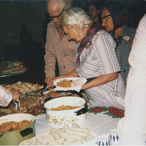 Elderly people standing in line and serving themselves food from a buffet