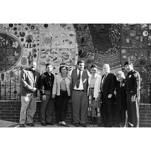 Eight men and women posing for a group photograph in front of the ceramic tile mural.