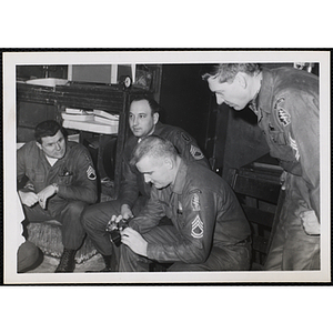 Several men wearing U.S. Army uniform examine a camera at a photographic laboratory