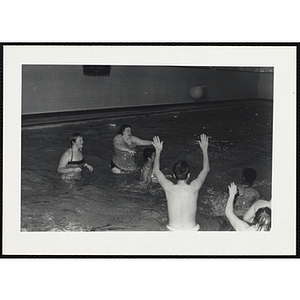 Teenagers play with a ball in a natorium pool