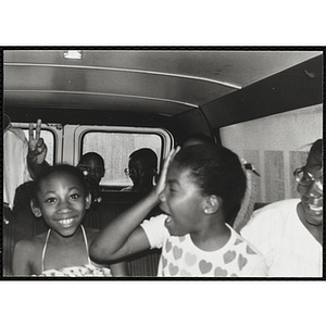 A group of children smile and laugh in a van