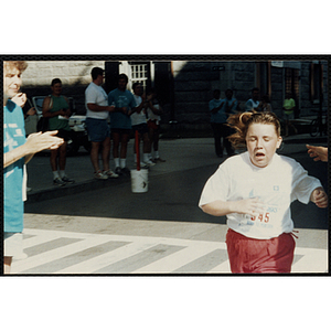 Welcomed by race officials, a girl finishes the Battle of Bunker Hill Road Race