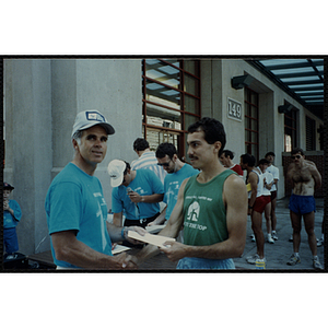 A man hands another man a certificate and shakes his hand during the Battle of Bunker Hill Road Race