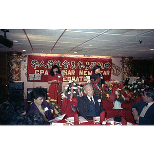 Two women address a crowd gathered at a restaurant to celebrate the Lunar New Year with the Chinese Progressive Association