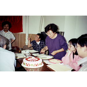 Suzanne Lee cuts pieces of her birthday cake for members at an Association meeting