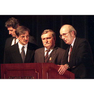 Lech Walesa, Dean Robert Lowdnes, and another man stand at a podium at the inauguration of the International Degree Program