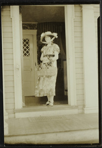Woman stands in the doorway of a house, location unknown, undated