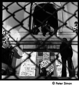 Civil War memorial on Cambridge Common seen through a chain link fence with protesters and antiwar signs
