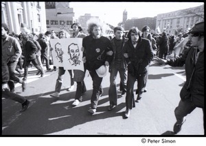 Protestors linking arms and carrying signs with the bust of Ho Chi Minh