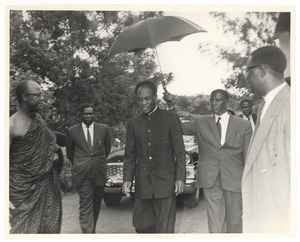 Unidentified man holds an umbrella over the head of Kwame Nkrumah at the state funeral of W. E. B. Du Bois