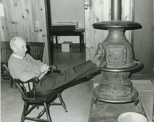 Dr. Chester Ellsworth Cross sitting indoors with his feet up on a wood stove