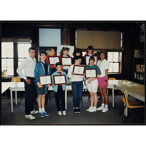 A man and a woman pose with a boy and seven girls displaying their certificates at a Boys & Girls Club awards event